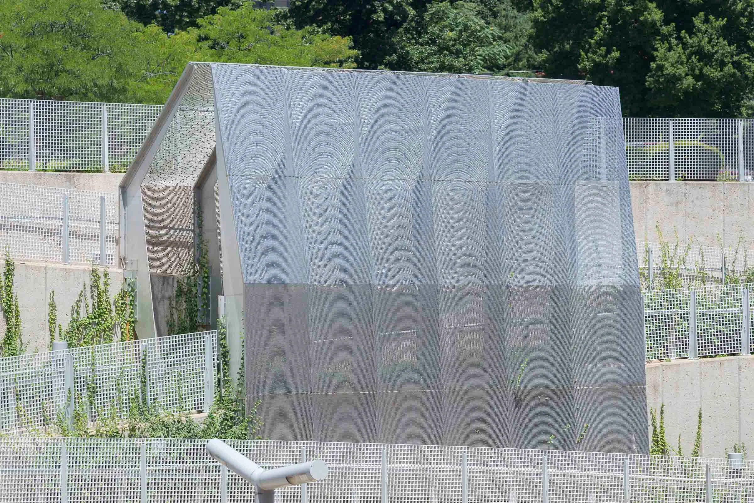 A perforated metal screen standing on a concrete wall above the platform
