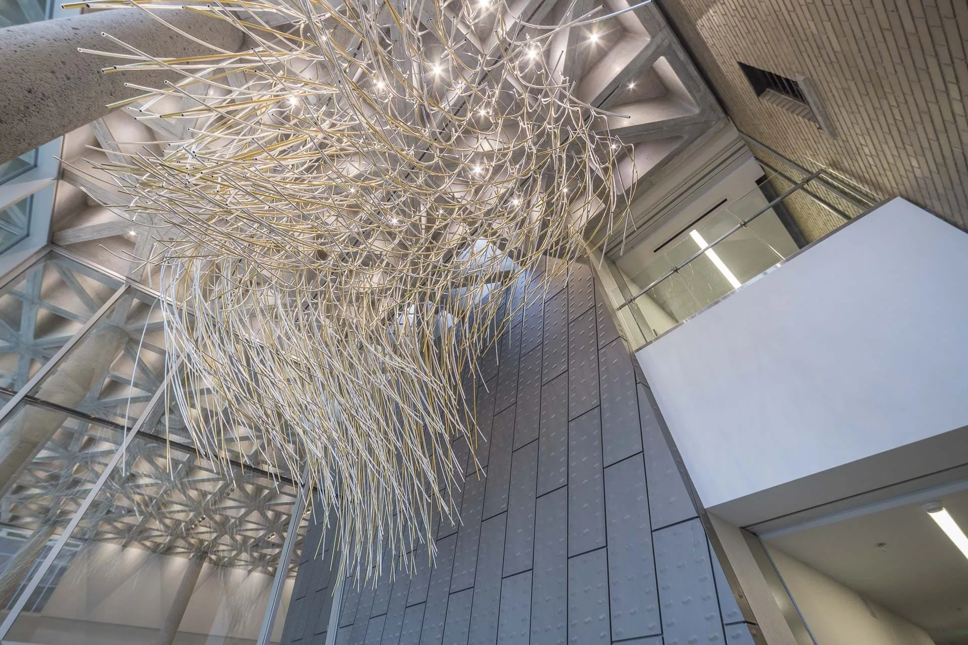 A suspended sculpture of white rods over a zinc-clad atrium
