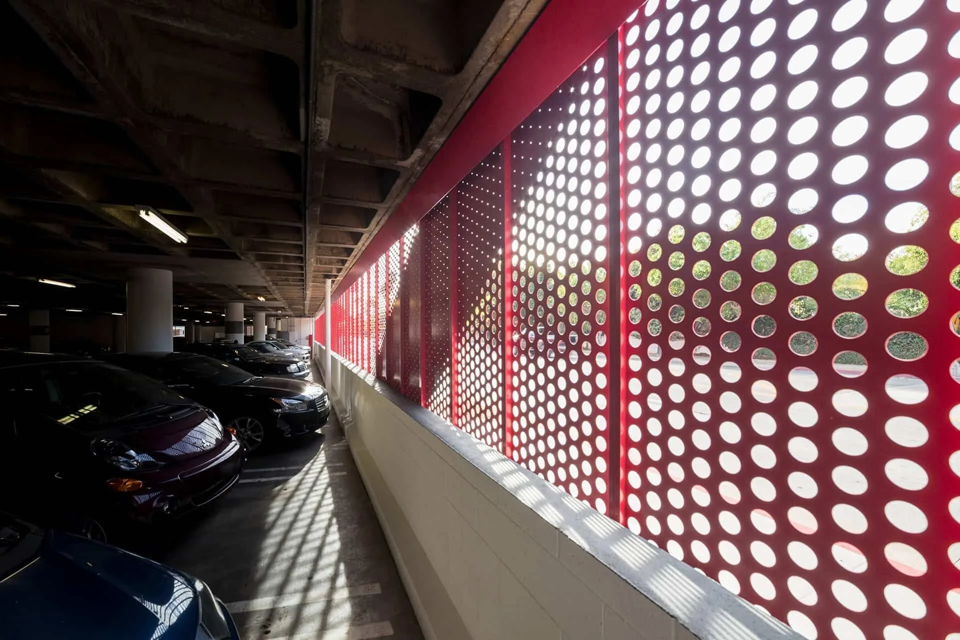 A perforated red screen along a parking deck
