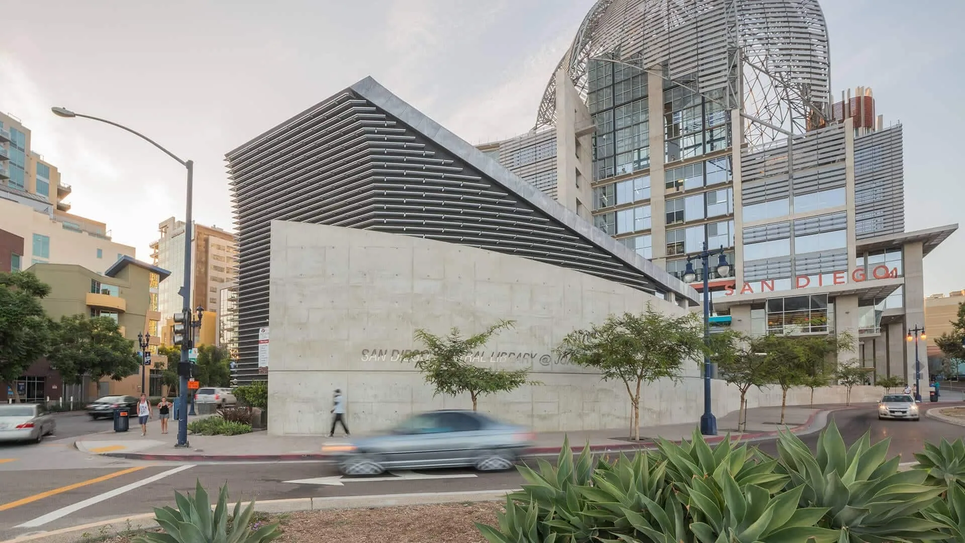 The library’s concrete wall and dome above a palm-lined street