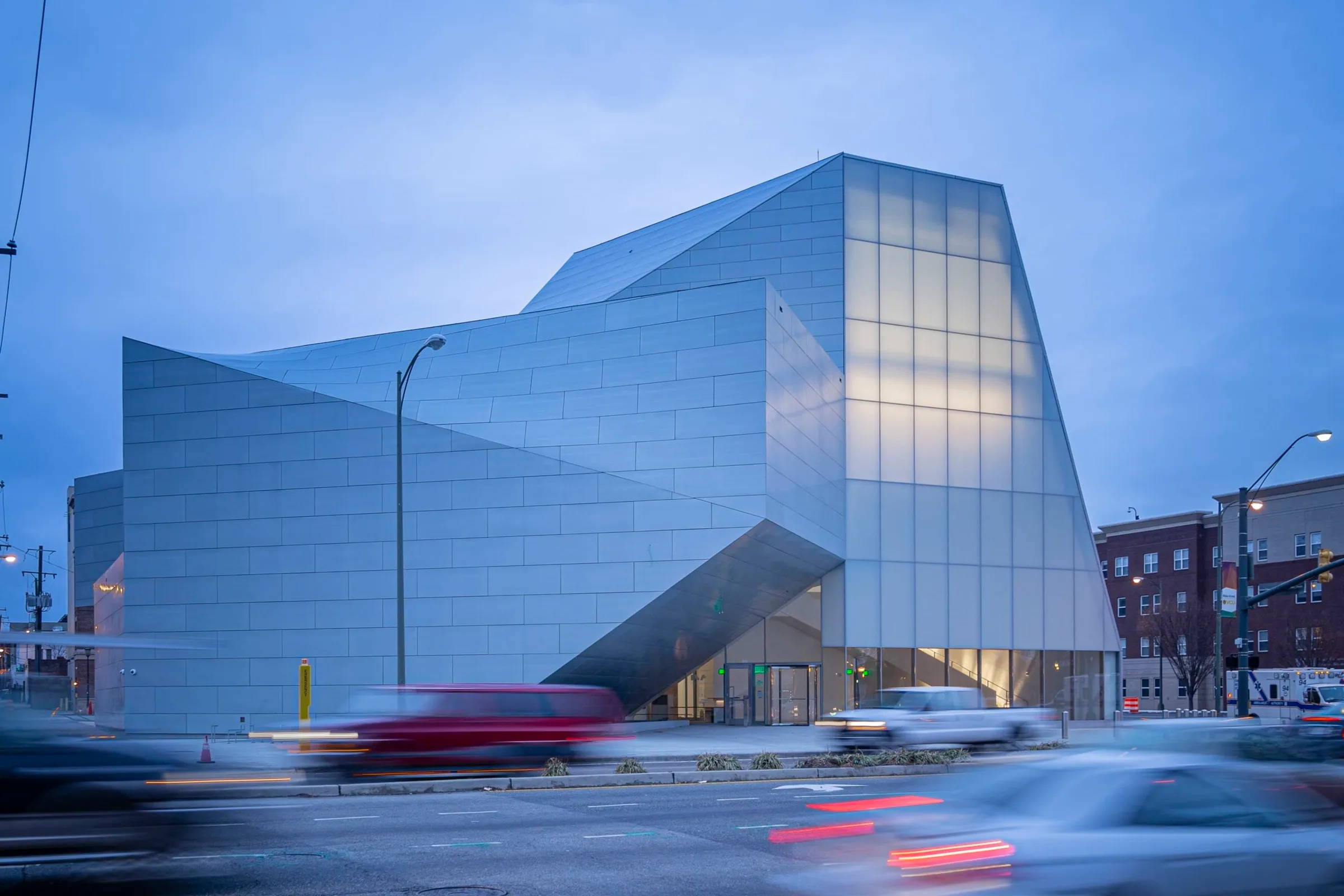 The ICA’s folded zinc volumes at dusk, car lights streaking past