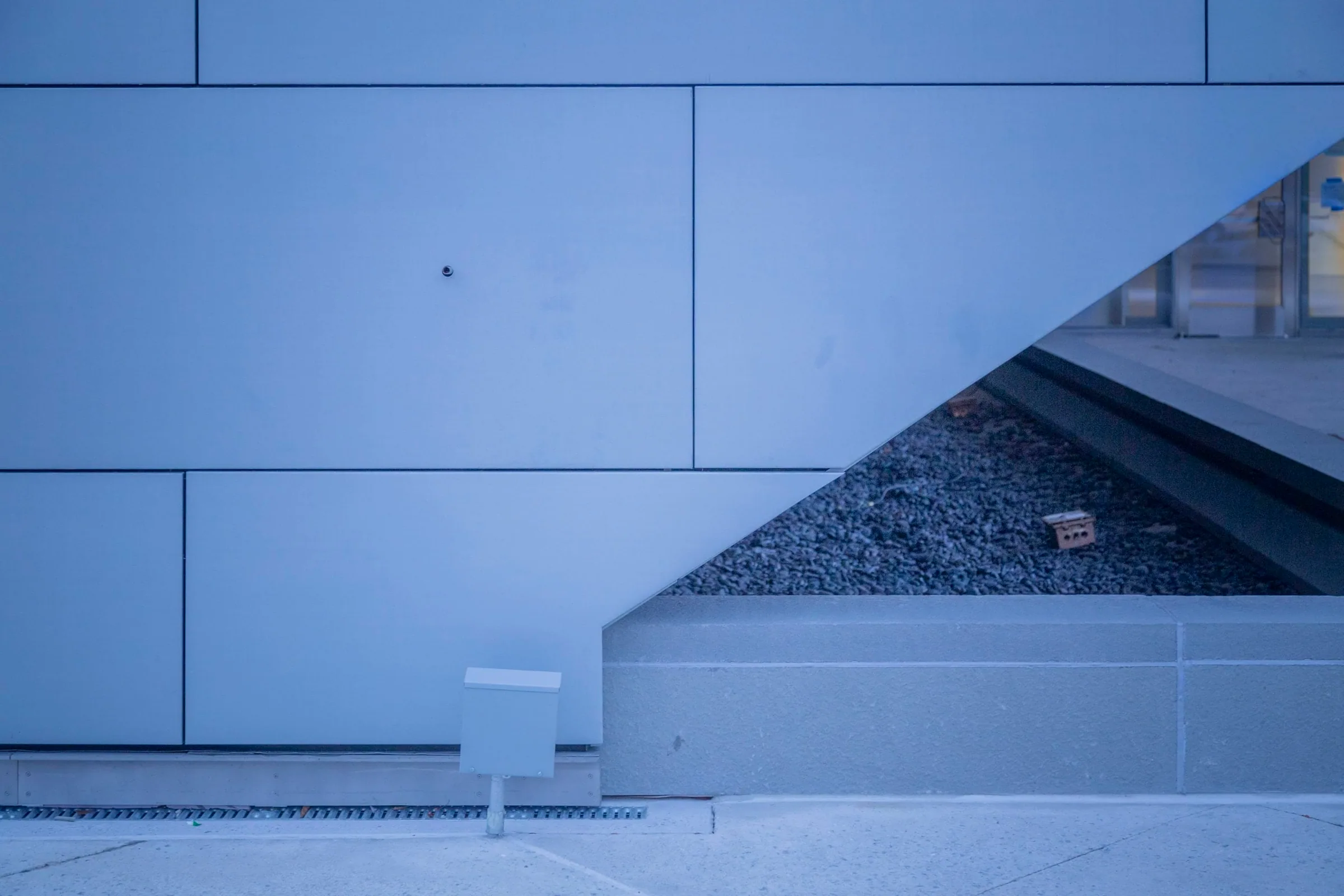 A zinc wall sloping down to a gravel bed