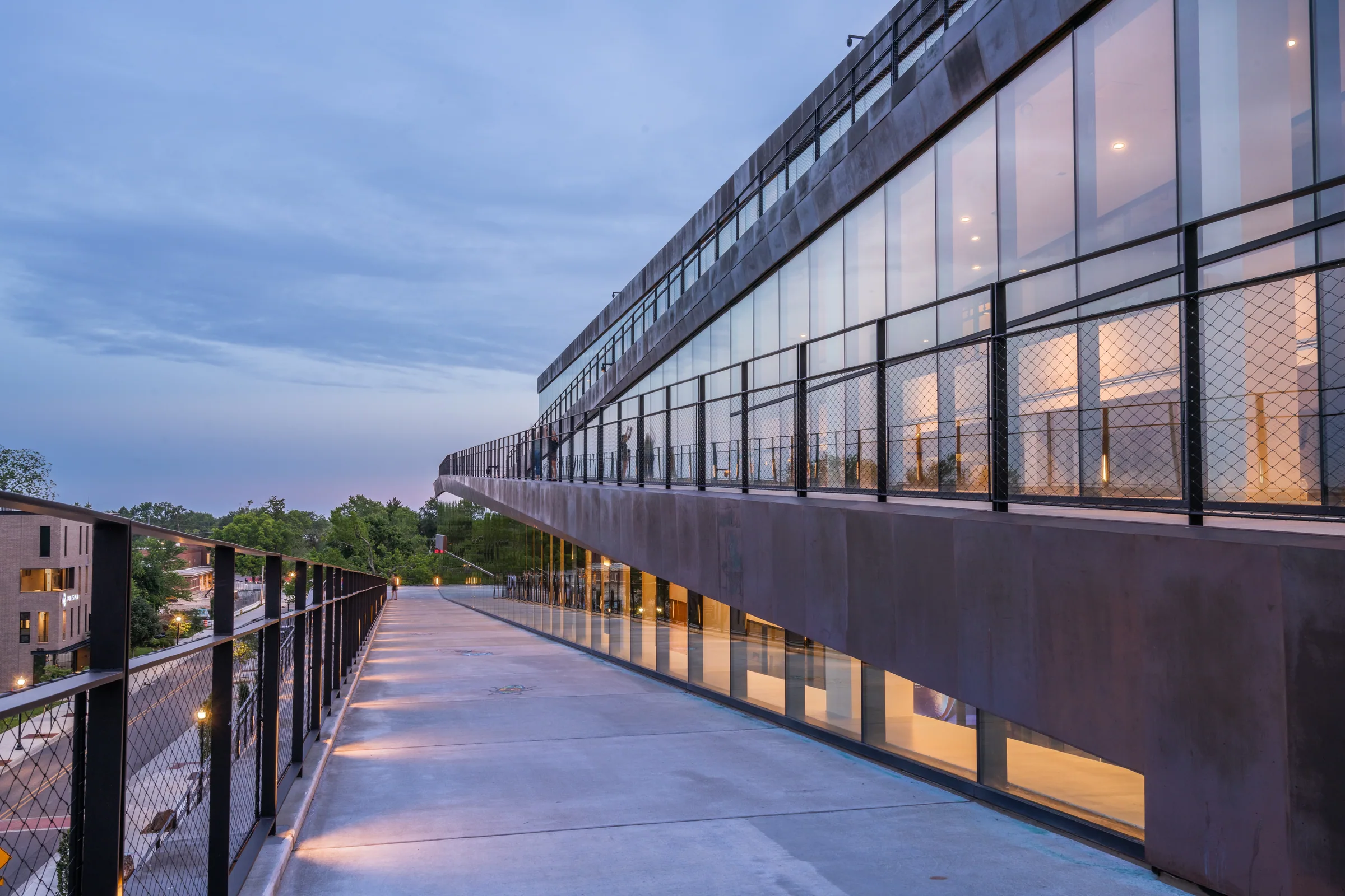 A lit walkway rising along the copper ramp at dusk
